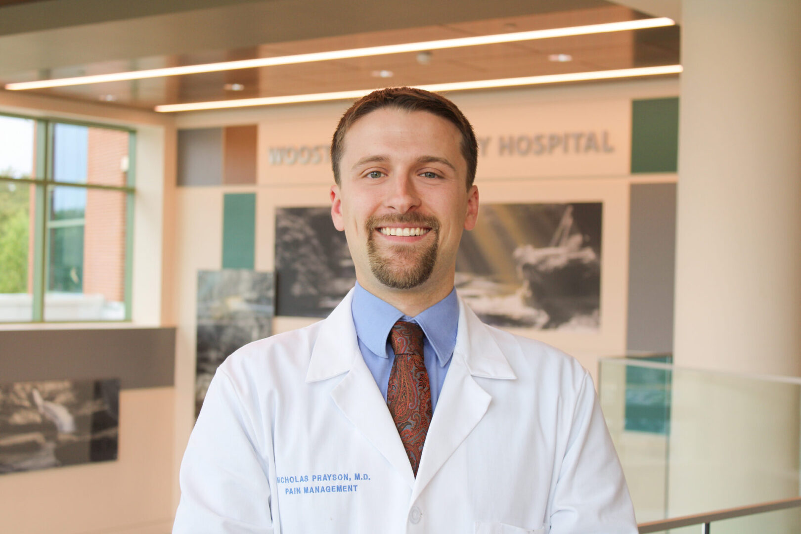 A man in white lab coat standing next to a wall.